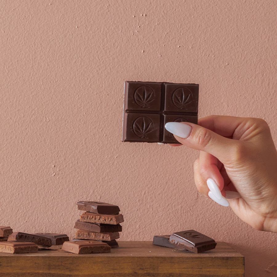 Person eating a chocolate bar with marijuana leaf stamped  - Sample / 1 Square